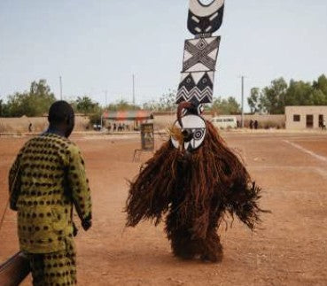 A Bwa plank mask dancer in a fiber costume in Burkina Faso