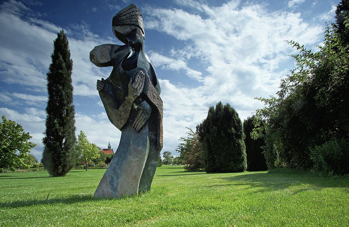 A tall Shona stone sculpture of two figures standing on a lawn