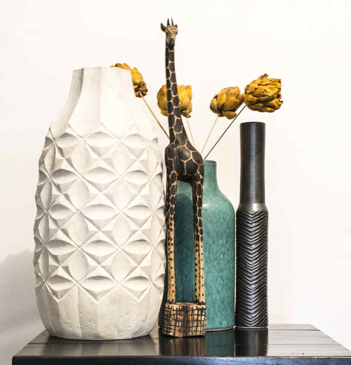 A small giraffe among vases