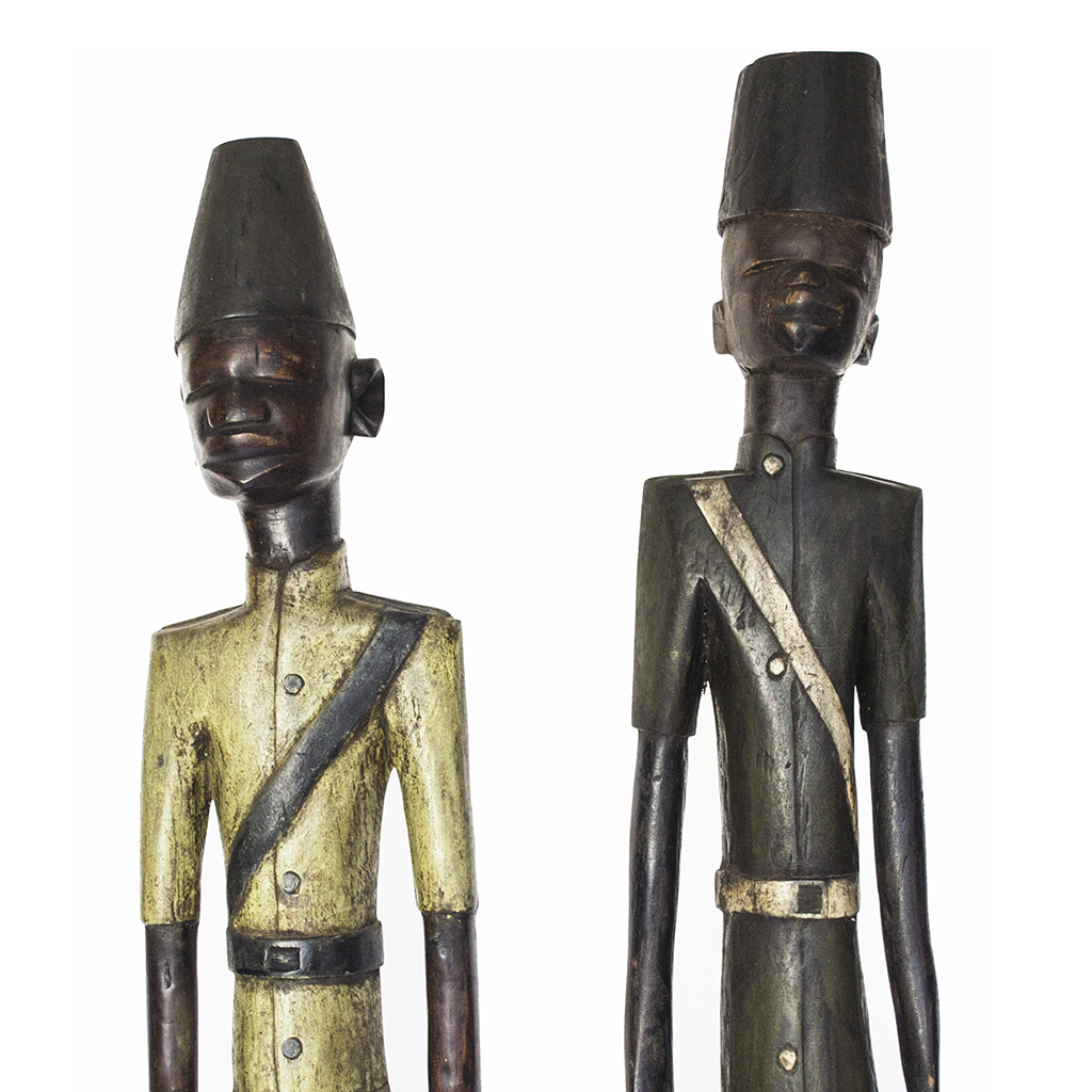 Colonial People, two Baule figures of colonial officials in painted uniforms and tall hats, carved from wood in Ivory Coast