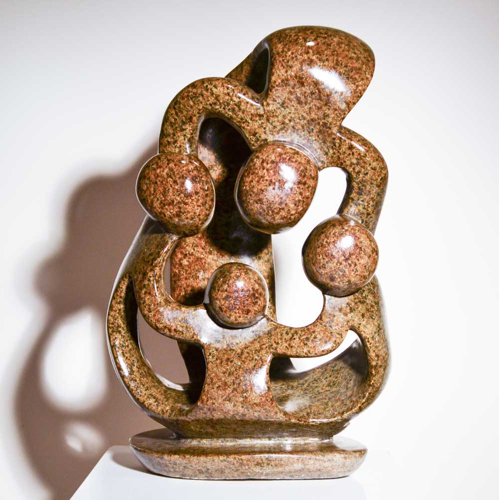 Family of Four by Agrippa Ndongwe, a Shona sculpture of four joined figures carved from brown serpentine stone in Zimbabwe