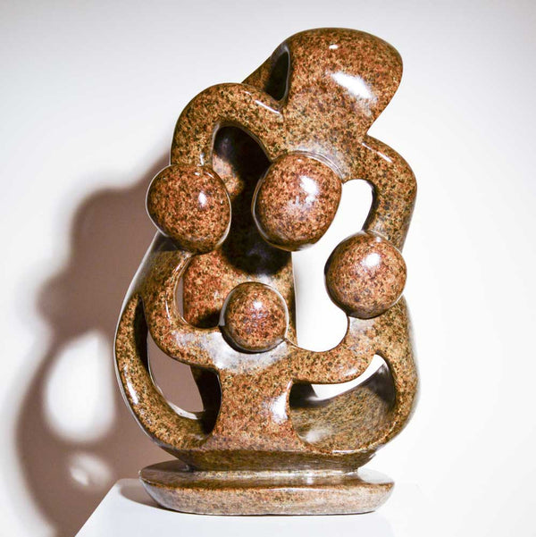 Family of Four by Agrippa Ndongwe, a Shona sculpture of four joined figures carved from brown serpentine stone in Zimbabwe