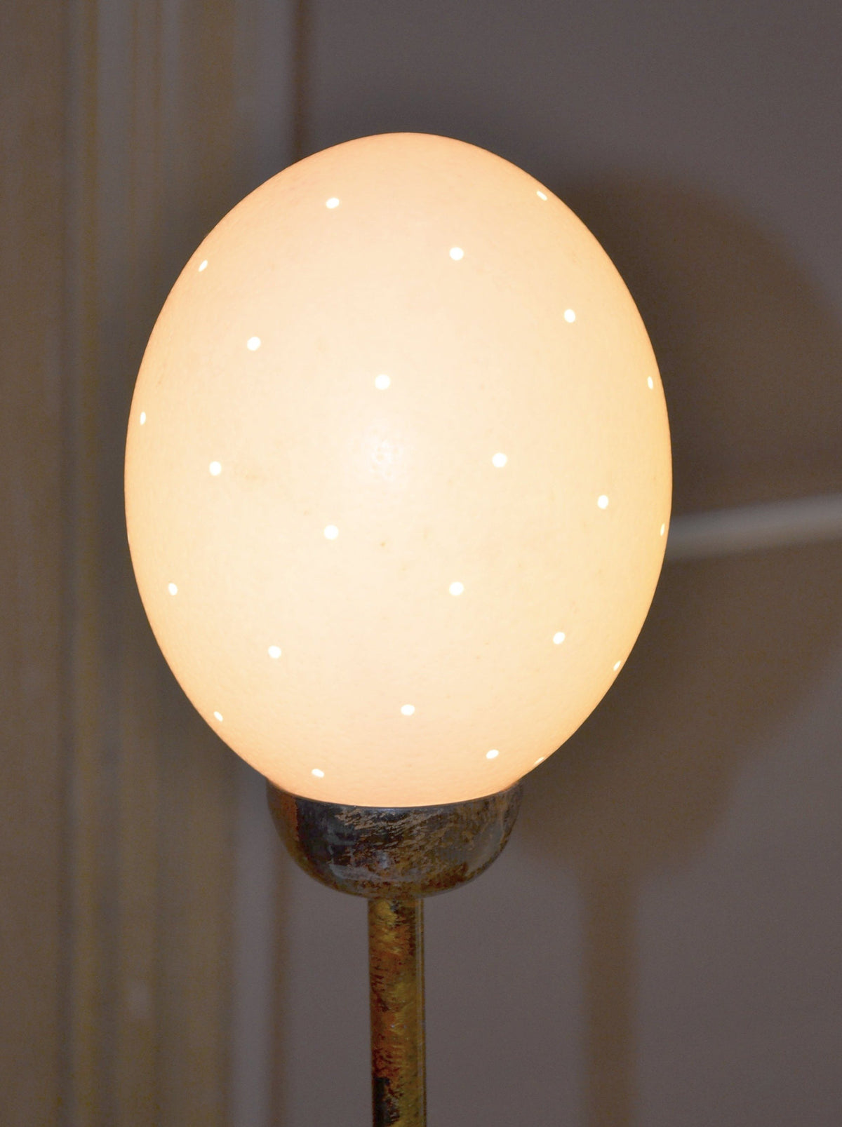 Ostrich Egg Table Lamp, a lamp made from an ostrich egg and painted metal in South Africa, lit to show its small holes