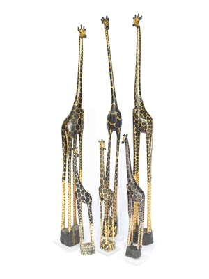 Giraffe, hand painted giraffes carved from teak wood in Zambia, shown in a group of three tall and three small