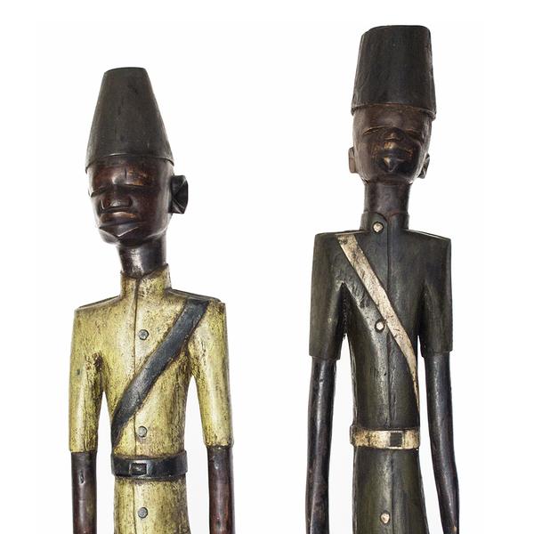 Colonial People, two Baule figures of colonial officials in painted uniforms and tall hats, carved from wood in Ivory Coast