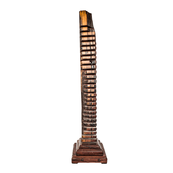 CD Rack, a tall sculpture carved from red jarrah wood in Zimbabwe, with slots cut down one side and a stepped square base