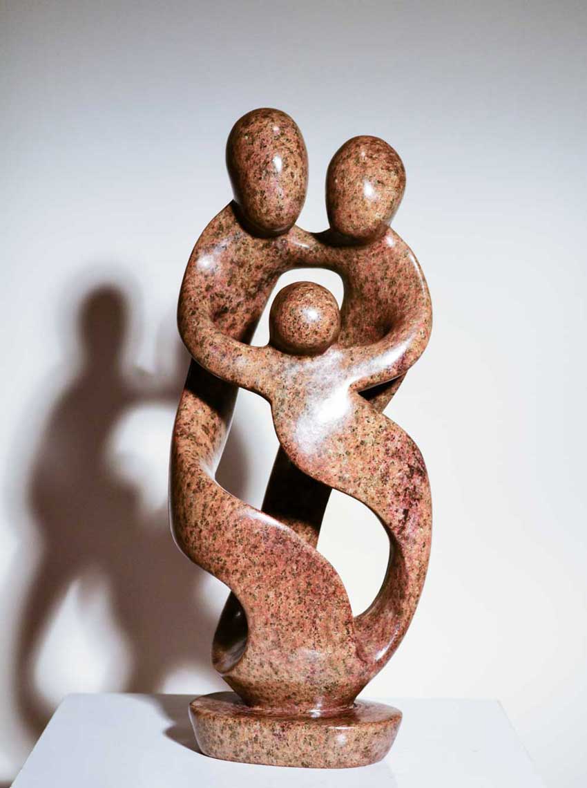 Family of Three by Agrippa Ndongwe, a Shona sculpture of a family carved from pink speckled serpentine stone in Zimbabwe